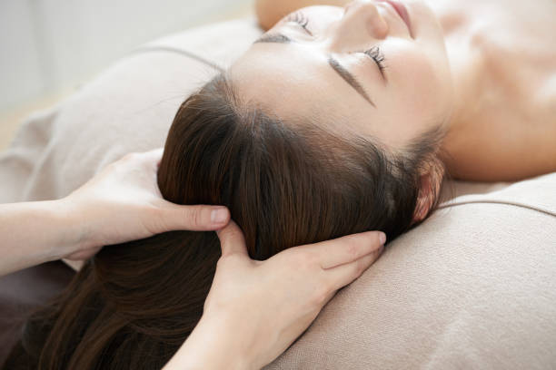 donna che riceve un massaggio alla testa in un luminoso salone di bellezza - head massage massaging beauty treatment massage therapist foto e immagini stock