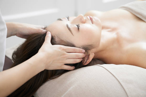 kobieta otrzymująca masaż głowy w jasnym salonie kosmetycznym - head massage headache massaging alternative therapy zdjęcia i obrazy z banku zdjęć