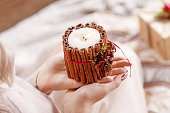 Burning candle in the hands of a girl. Christmas candle. Christmas decor. Woman's hands holding beautiful candle with fire. Copy space