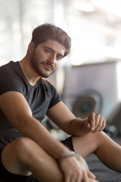 istock Tired young man sitting on bench in gym 1186240371
