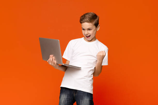 istock Excited teen boy using laptop computer, celebrating success 1186253459