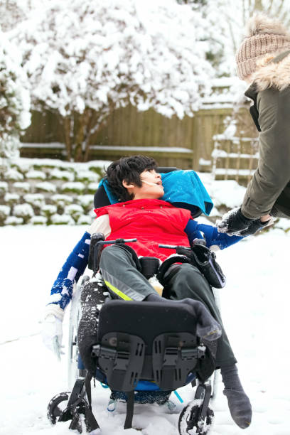 istock Disabled boy in wheelchair playing with snow in winter 1186253717