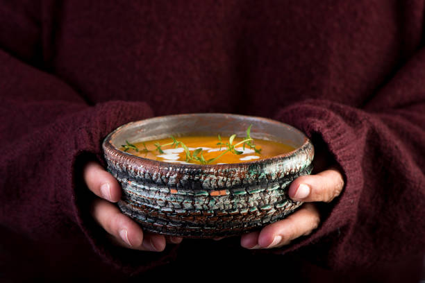 istock Hands with bowl of orange pumpkin soup. Selective focus. 1186254573