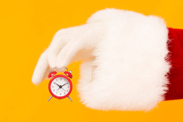 istock Santa holding retro red alarm clock on orange 1186255614