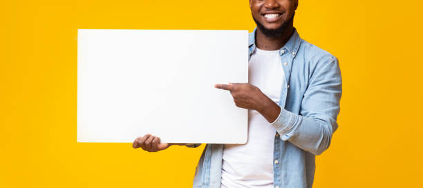 istock Black man holding white advertising board and pointing on it 1186255689