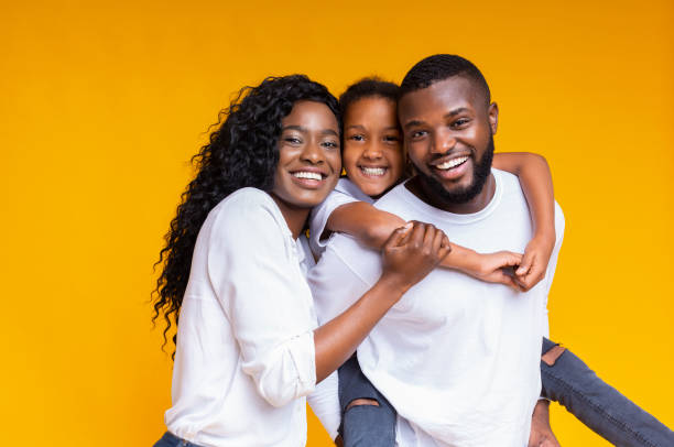 felici genitori afroamericani in posa con la loro bambina - family african descent cheerful happiness foto e immagini stock