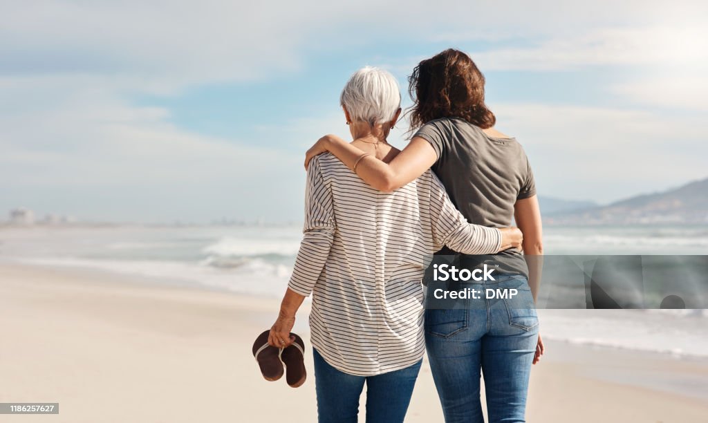 All you need is family…and beach Rearview shot of a young woman going for a walk along the beach with her elderly mother Mother Stock Photo