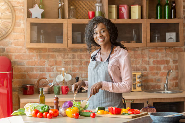 istock Joyful african lady mixing veggies in bowl in kitchen 1186257775