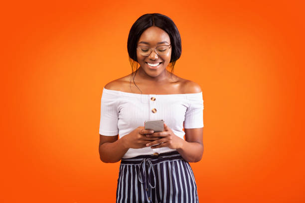 istock Smiling Black Lady Standing Using Smartphone And Chatting, Studio Shot 1186261222