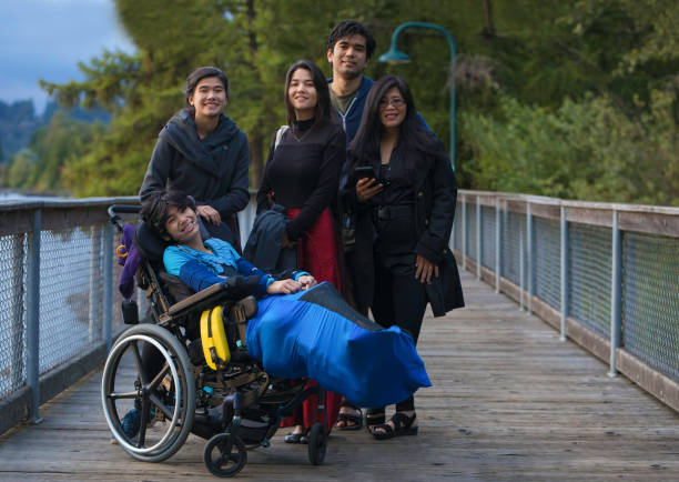 Asian mother with adult children and disabled  son in wheelchair stock photo