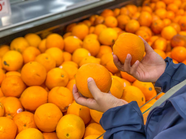 istock Human hand holding and choosing fresh oranges at fruit store 1186263231