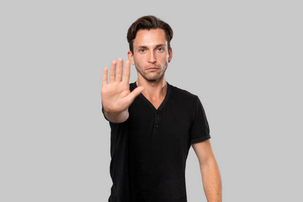 istock Confindent handsome man in a black tee shirt showing Stop gesture isolated over grey background. 1186263349