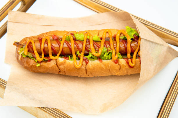 hot dog con insalata e cetrioli con ketchup di pomodoro e senape su sfondo bianco. fast food gustoso e bello su un retro leggero. - sausage grilled isolated single object foto e immagini stock