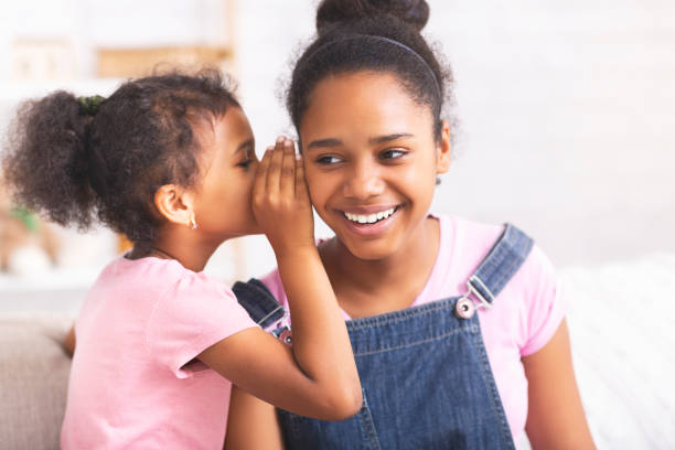 istock Playful african sister whispering secrets at home 1186271220