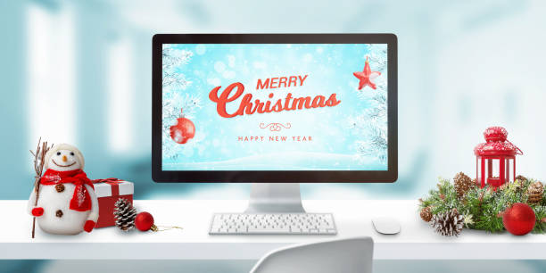 Christmas in office concept. Merry Christmas greeting on computer display. Christmas decorations on work desk.