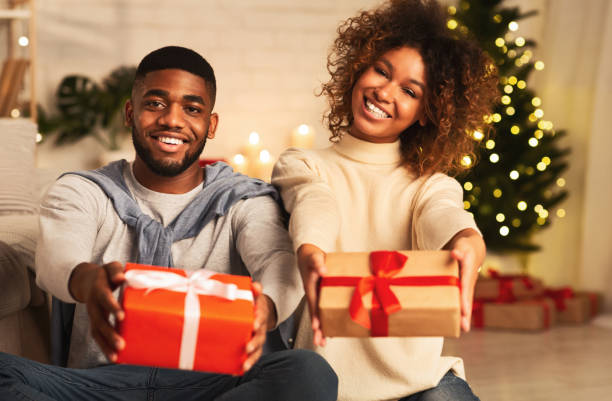 ¡feliz año nuevo! feliz pareja afro sosteniendo regalos de navidad - stretching boyfriend indoors lifestyles fotografías e imágenes de stock