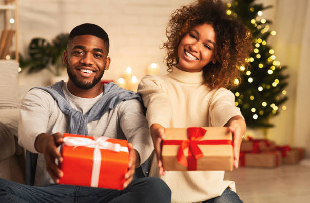 szczęśliwego nowego roku! szczęśliwa para afro trzymająca prezenty xmas - stretching boyfriend indoors lifestyles zdjęcia i obrazy z banku zdjęć