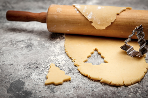 Cookie dough and rolling pin on grey table, christmas tree shaped cookie cutter