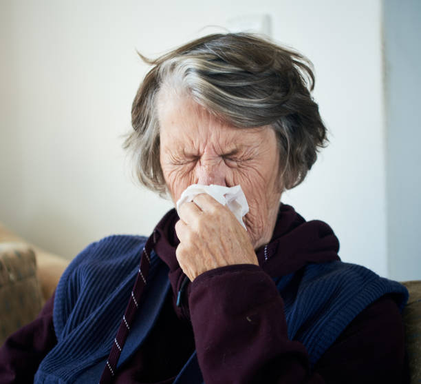 istock Senior woman sneezes into a tissue 1186275767