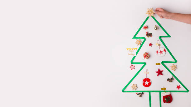 istock Woman decorating with star Christmas tree on white 1186276938