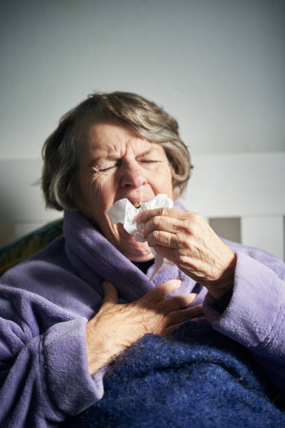 donna anziana a letto con starnuti influenzale miseramente - miseramente foto e immagini stock