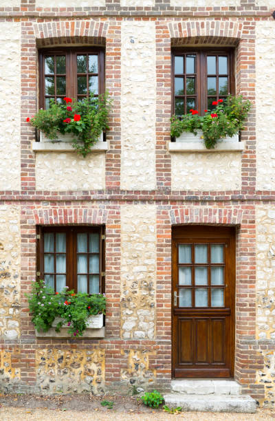 Jumieges, Normandy / France - 13 August 2019: typical Normandy architecture house front with stone and brick facade and colorful flowerpots