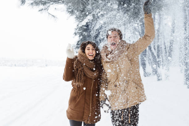 istock Happy Couple Throwing Snow Walking In Snowy Winter Forest 1186283917
