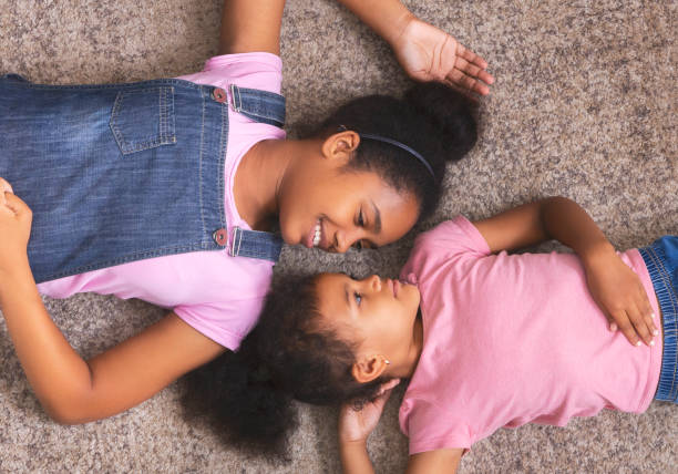 istock Loving african american sisters lying together on floor 1186284748