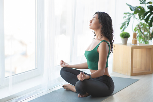 Young sporty woman practising yoga in lotus position