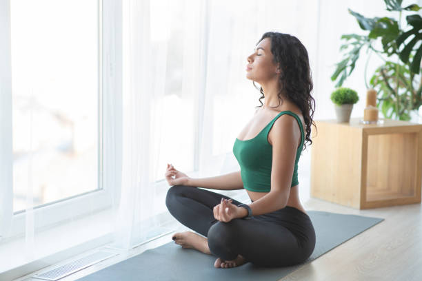 young sporty woman practising yoga in lotus position - atividades relaxantes imagens e fotografias de stock