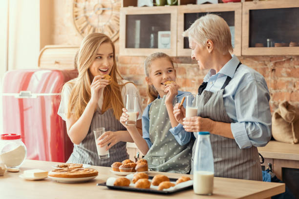 キッチンで調理した後、スナックを持っている肯定的な家族 - grandmother pie cooking baking ストックフォトと画像