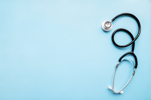 Stethoscope on pastel blue table. Doctor tool. Healthcare concept. Empty place for text. Flat lay. Closeup. Top down view.