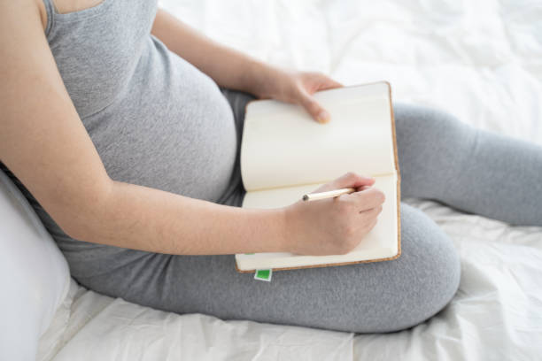 istock Pregnant woman makes notes in notebook. pregnancy, parenthood, preparation and expectation concept. 1186290193