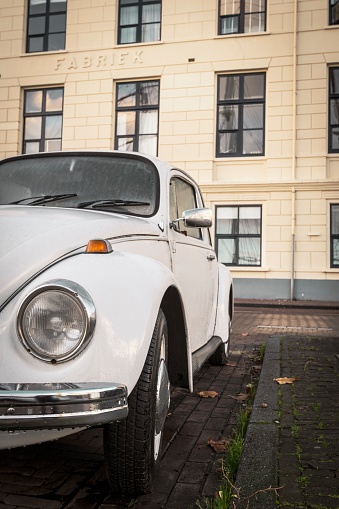 VW Beetle or officially the Volkswagen Type 1 classic car parked in front of an old factory on the quay in the city of Kampen, Overijssel, The Netherlands.