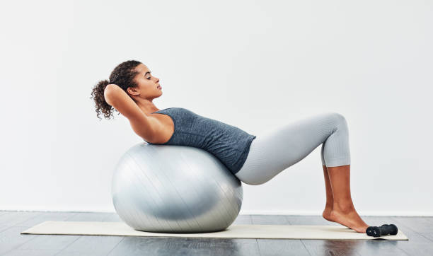 Work towards small achievements each day Shot of a young woman exercising using a fitness ball fitness ball photos stock pictures, royalty-free photos & images