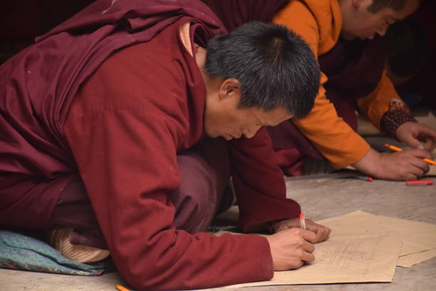 Buddhist monk practicing drawing a mandala inside Sakya monastery, Tingri county, Tibet - China Mandala is a spiritual and ritual geometric configuration of symbols or a map representing deities or shrines. The basic form of most mandalas is a square with four gates containing a circle with a center point. tingri stock pictures, royalty-free photos & images