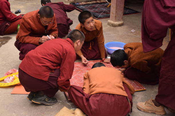 Buddhist monks practicing drawing a mandala inside Sakya monastery, Tingri county, Tibet - China Mandala is a spiritual and ritual geometric configuration of symbols or a map representing deities or shrines. The basic form of most mandalas is a square with four gates containing a circle with a center point. tingri stock pictures, royalty-free photos & images