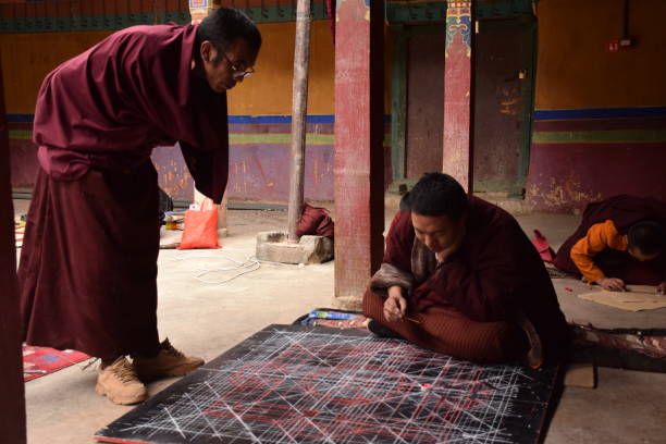 Buddhist monk practicing drawing a mandala inside Sakya monastery, Tingri county, Tibet - China Mandala is a spiritual and ritual geometric configuration of symbols or a map representing deities or shrines. The basic form of most mandalas is a square with four gates containing a circle with a center point. tingri stock pictures, royalty-free photos & images