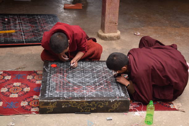 Buddhist monks practicing drawing a mandala inside Sakya monastery, Tingri county, Tibet - China Mandala is a spiritual and ritual geometric configuration of symbols or a map representing deities or shrines. The basic form of most mandalas is a square with four gates containing a circle with a center point. tingri stock pictures, royalty-free photos & images