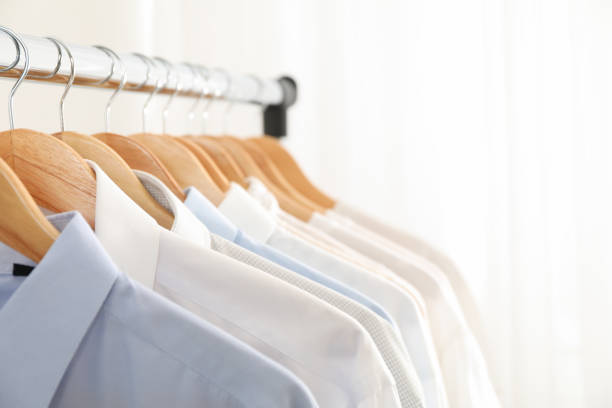 istock Hangers with shirts against light background, copy space 1186299871