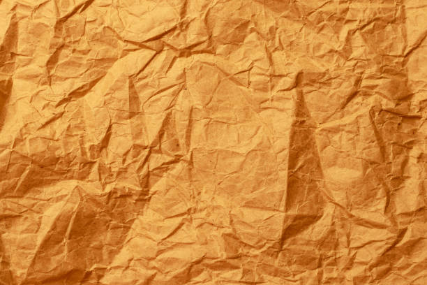 Damaged yellow paper. Orange crumpled sheet. Packaging. Rough texture background. Parchment surface. stock photo