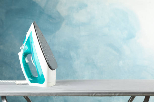 istock Iron on ironing board against blue background, space for text 1186301159