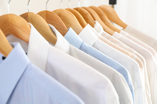 istock Hangers with shirts against light background, close up 1186301229