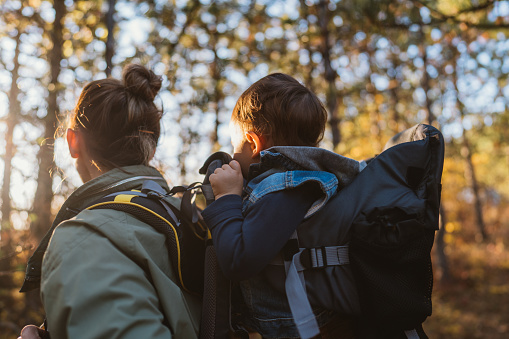 Photo of young mother spending time with her son by taking him on a hike while he is in a baby carrier backpack