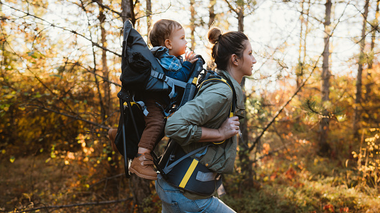 Photo of young mother spending time with her son by taking him on a hike while he is in a baby carrier backpack