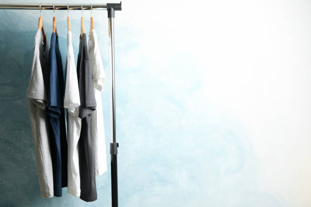 istock Rack with blank t-shirts on blue background, space for text 1186301723