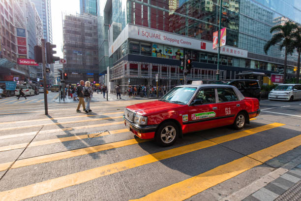 Hong Kong - October 3, 2019: A red taxi driving through yellow crossing at Tsim Sha Tsui.