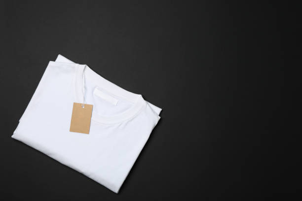 istock Folded blank white t-shirt with tag on black background, space for text 1186301742
