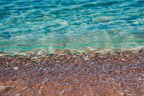 istock Turquoise sea waves splashing on pebble shore 1186302833