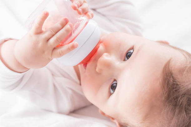 istock Baby boy lying on bed and drinking tea from her plastic bottle. 1186305740